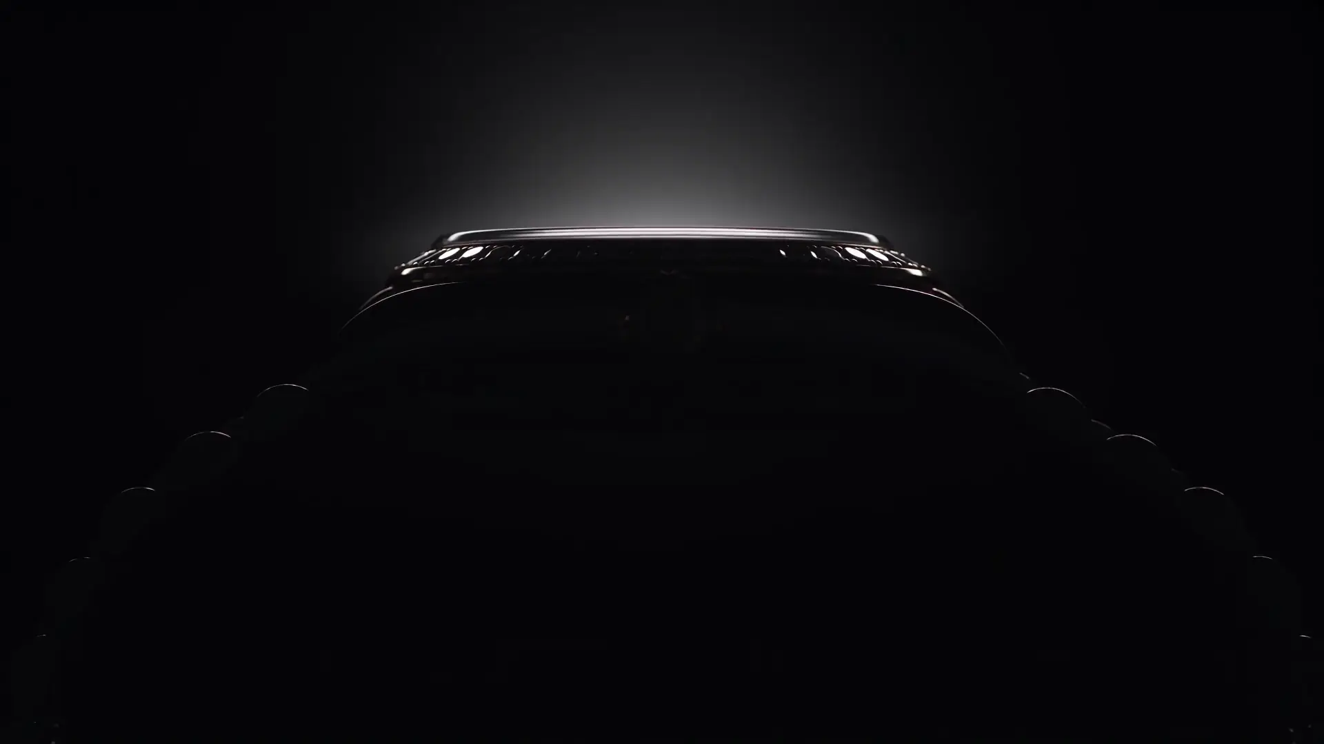 The first frame of the watch film: a thin rim of light on a watch case in darkness (illustrative, generated)